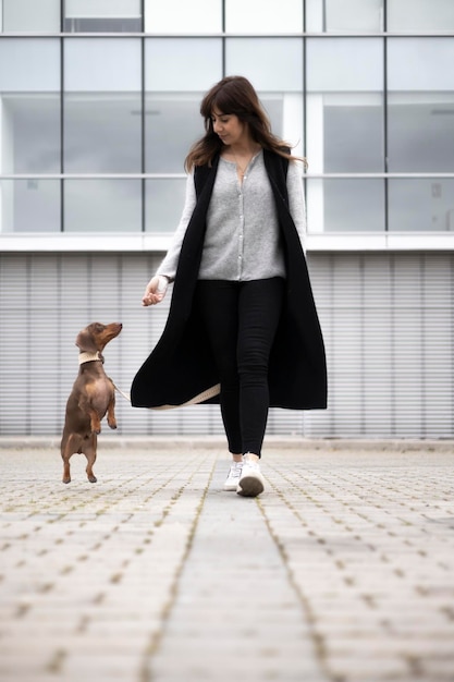 Ragazza che cammina per strada piccolo cane bassotto