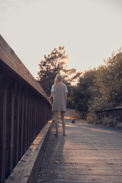 Ragazza che cammina sul ponte di legno Tranquillità al tramonto