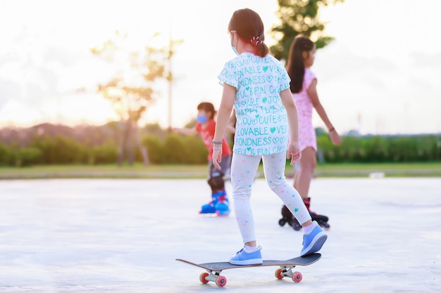 Ragazza che cavalca lo skateboard allo skatepark Divertente pattinatore che pratica ollie sullo skateboard al tramonto