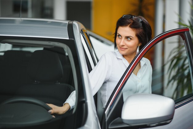 Ragazza che controlla una nuova automobile bianca in una concessionaria di automobili