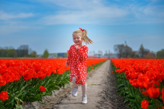 Ragazza che corre in un campo di tulipani rossi