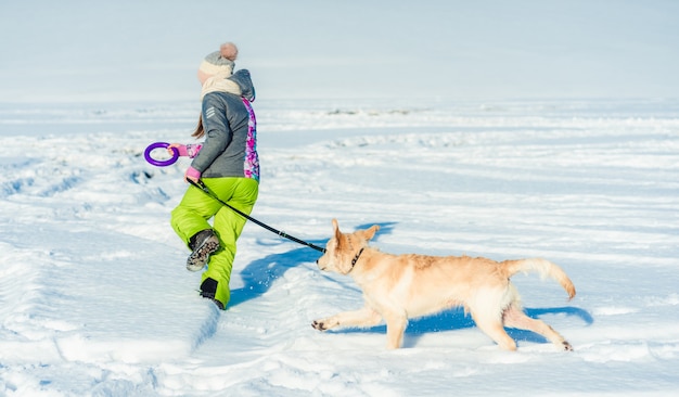 Ragazza che corre nella neve con il cane