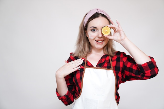 Ragazza che cucina, ragazza in grembiule, ragazza divertente macchiata di farina, ragazza con limone negli occhi