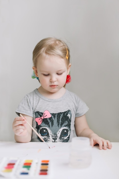 Ragazza che dipinge e disegna con la pittura ad acquerello a tavola lo sviluppo del potenziale creativo nei bambini