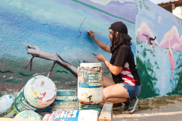 Ragazza che dipinge un muro di strada.