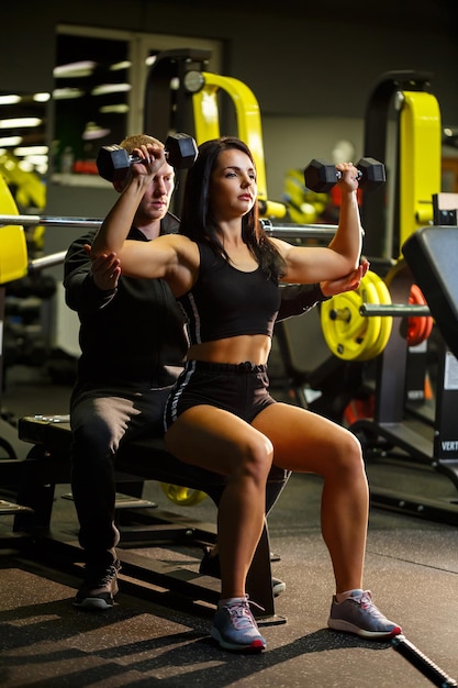 Ragazza che fa esercizi in palestra con un allenatore