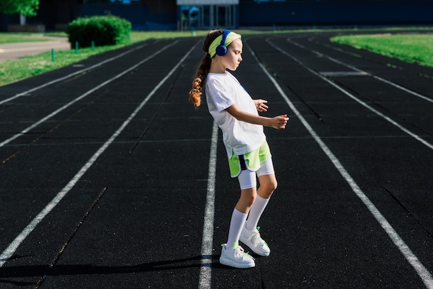 Ragazza che fa jogging in una soleggiata serata estiva, sdraiata su tapis roulant, stadio, allenamento fisico, ritorno a scuola.