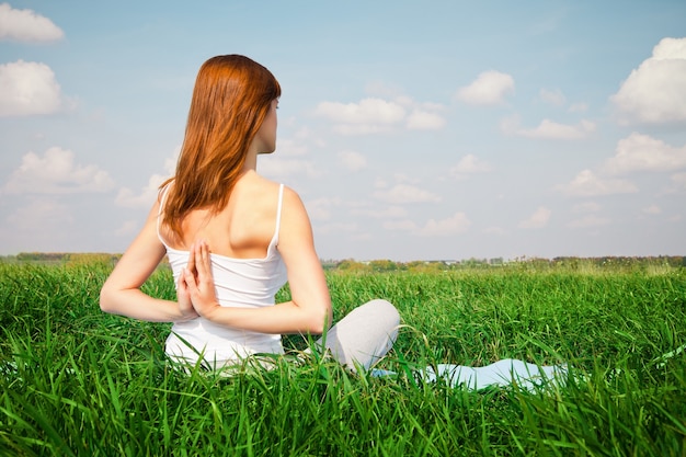 Ragazza che fa la posa del loto di yoga nel parco