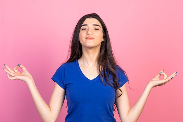 Ragazza che fa meditazione su sfondo rosa