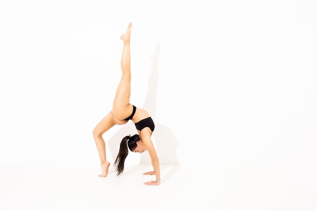 Ragazza che fa stretching in studio su sfondo bianco. Una bella ginnasta con un corpo flessibile e un'uniforme atletica.