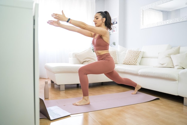 RAGAZZA CHE FA YOGA E PILATES NEL SALOTTO DI CASA CON IL COMPUTER