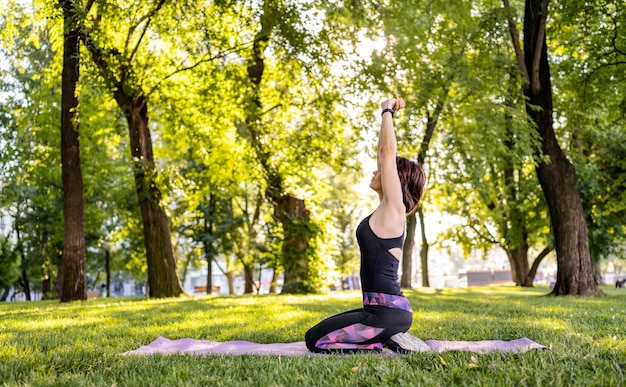 Ragazza che fa yoga mattutino e allunga il suo corpo al parco all'aperto in estate giovane donna exercisi