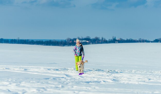 Ragazza che funziona con il cane in neve