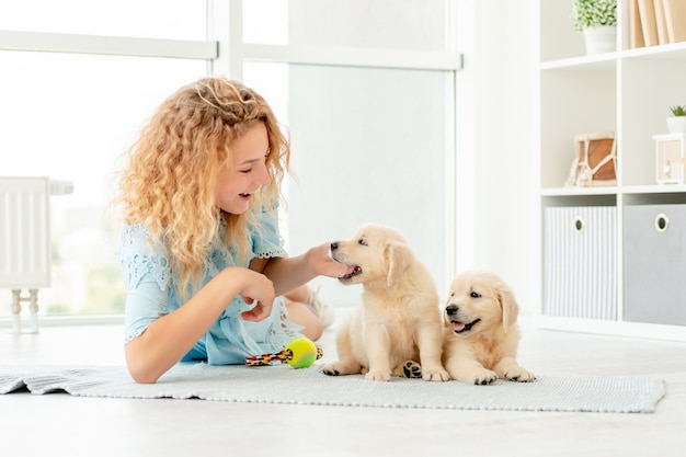 Ragazza che gioca con i cuccioli di retriever