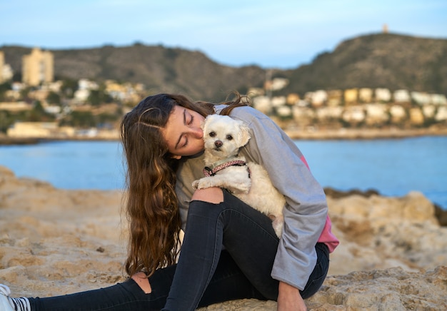 Ragazza che gioca con il cane di maltichon in spiaggia