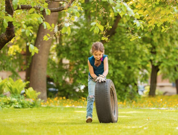 Ragazza che gioca con la ruota della macchina nel parco estivo