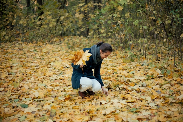 Ragazza che gioca con le foglie secche autunnali nel bosco