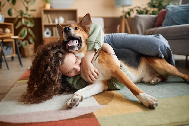 Ragazza che gioca con un cane felice che gioca sul pavimento a casa