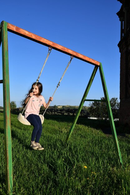 Ragazza che gioca sull'altalena nel parco giochi