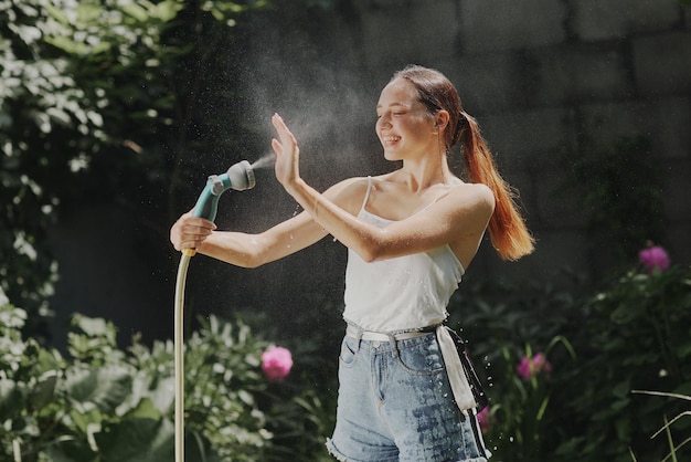 Ragazza che gode dell'acqua nella calura estiva in giardino