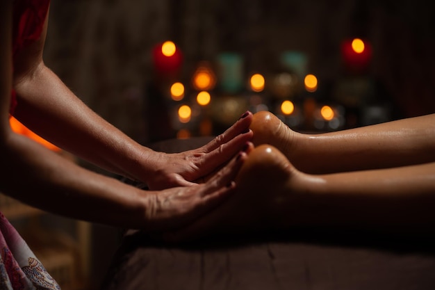 Ragazza che gode di un massaggio terapeutico con olio nella spa con illuminazione scura, primo piano
