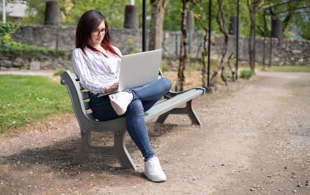 Ragazza che guarda una maglietta e guarda un laptop in un parco