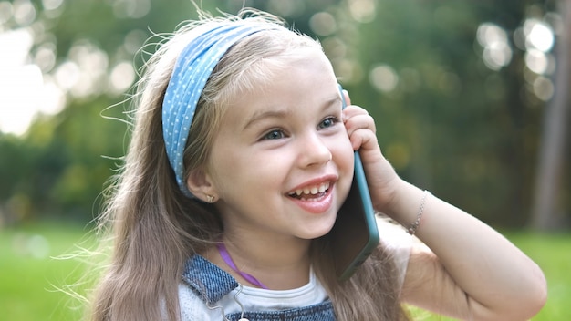 ragazza che ha conversazione parlando al cellulare nel parco estivo