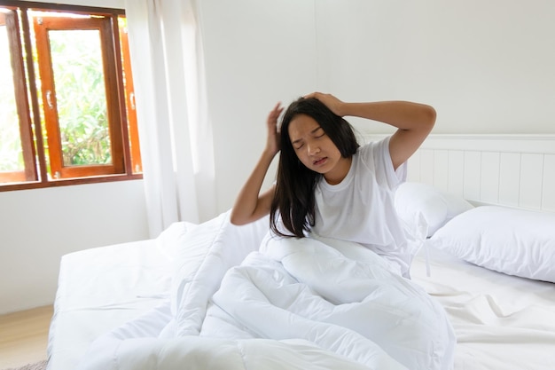 Ragazza che ha mal di testa sul letto in camera da letto a casa