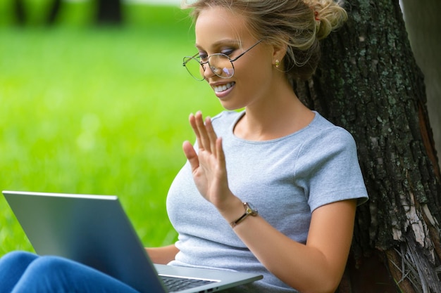 Ragazza che ha una videochiamata con i colleghi sul laptop di briefing online seduto nel primo piano del parco