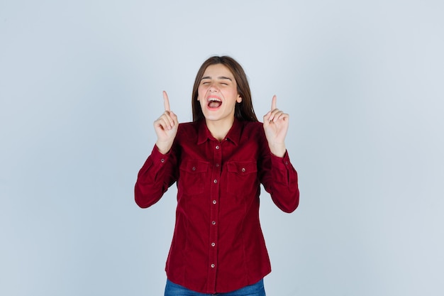 ragazza che indica in su in camicia casual e sembra beata