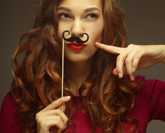 Ragazza che indossa baffi finti. Pronto per la festa.