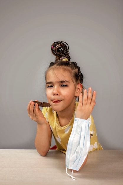 Ragazza che indossa la sua maschera respiratoria medicina e mangia barrette di cioccolato con piacere