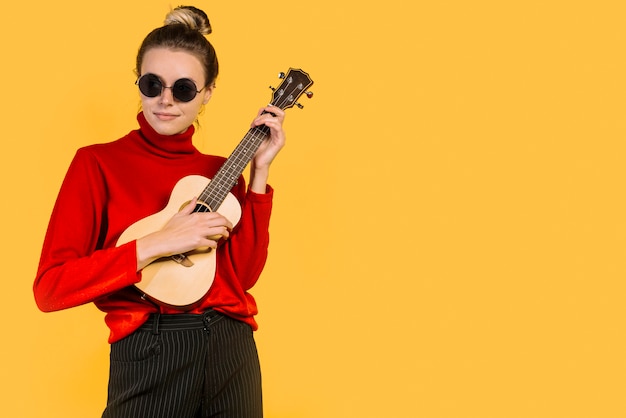 Ragazza che indossa occhiali da sole suonare l&#39;ukelele