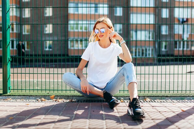 Ragazza che indossa t-shirt e occhiali in posa contro la strada