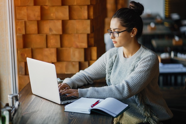 Ragazza che lavora su un computer portatile in un ristorante