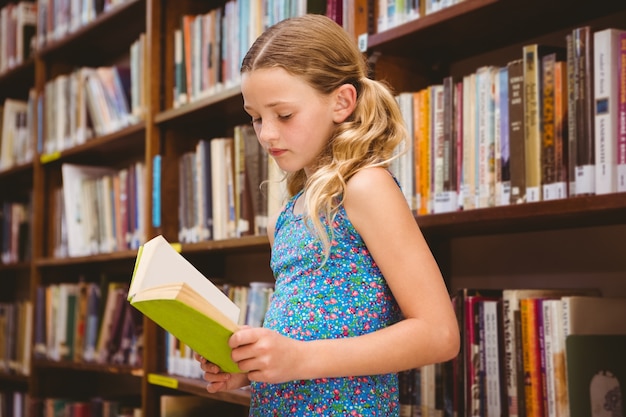 Ragazza che legge il libro in biblioteca