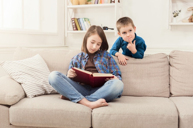 Ragazza che legge un libro per suo fratello