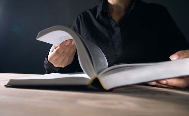 Ragazza che legge un libro su sfondo scuro