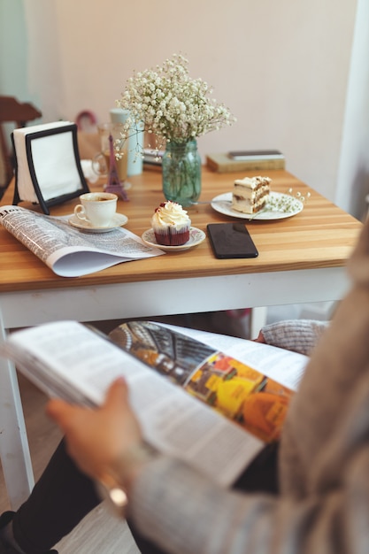 Ragazza che legge una rivista davanti a un tavolo con diversi dessert