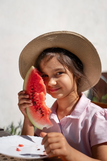 Ragazza che mangia anguria all'aperto a tavola