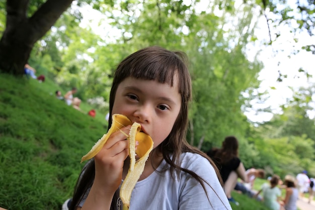 Ragazza che mangia banana nel parco