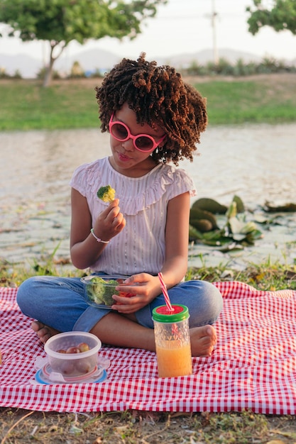 Ragazza che mangia broccoli nel parco