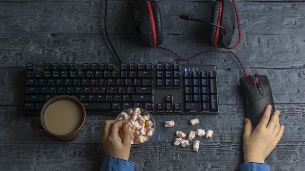 Ragazza che mangia caramelle gommosa e molle colorate che si siedono al computer di gioco