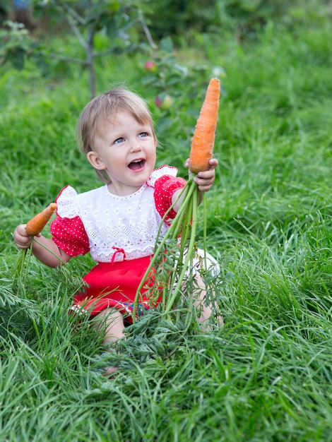 Ragazza che mangia carote fresche in giardino