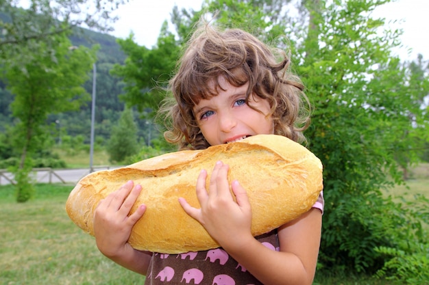 Ragazza che mangia il bambino affamato di grande dimensione di umore del pane