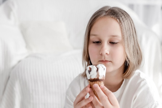 Ragazza che mangia il gelato con lo sfondo del soggiorno a casa La ragazza del bambino si diverte a mangiare e al concetto di fame