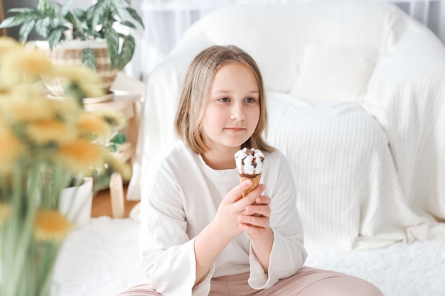 Ragazza che mangia il gelato con sfondo soggiorno a casa. La ragazza del bambino gode del concetto di mangiare e affamato.