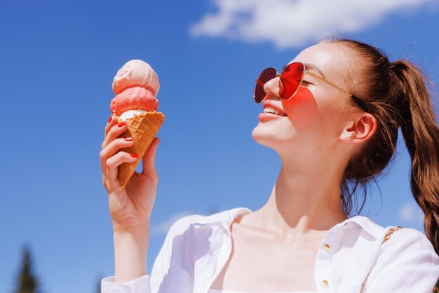 Ragazza che mangia il gelato in un cono vicino nella calda estate