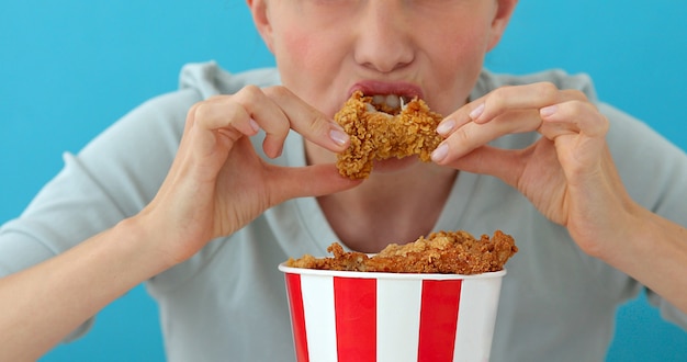 Ragazza che mangia le ali di pollo