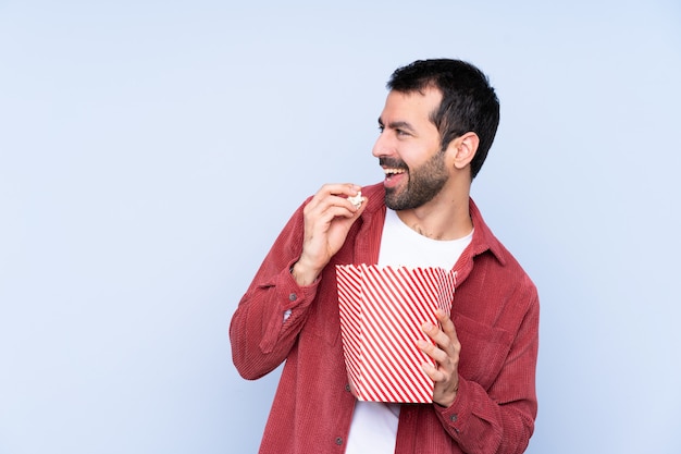 Ragazza che mangia popcorn mentre si guarda un film sopra la parete isolata